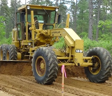 motor grader with carbide scarifier bits for road maintenance